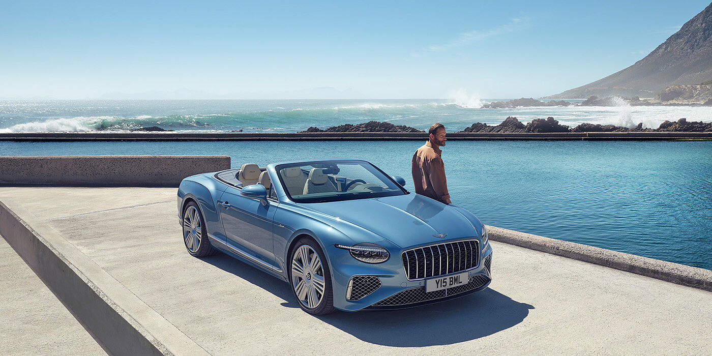 Bentley Panama New Bentley Continental GTC Azure convertible front view in Light Windsor blue paint with 22 inch ten spoke wheels parked by the sea in the sunshine
