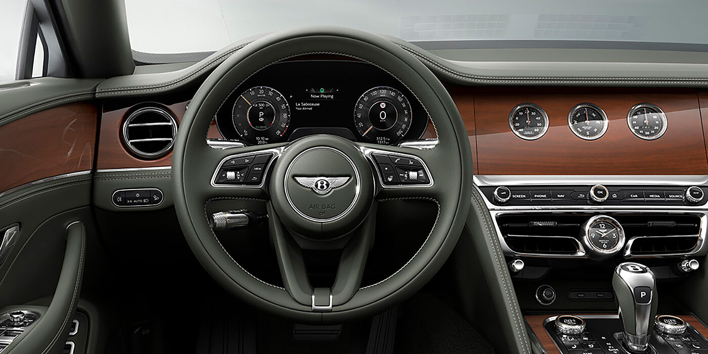 Bentley Panama New Bentley Flying Spur sedan front cabin in Cumbrian Green hide and Crown Cut walnut veneer showing steering wheel and Rotating Display with three clocks on face