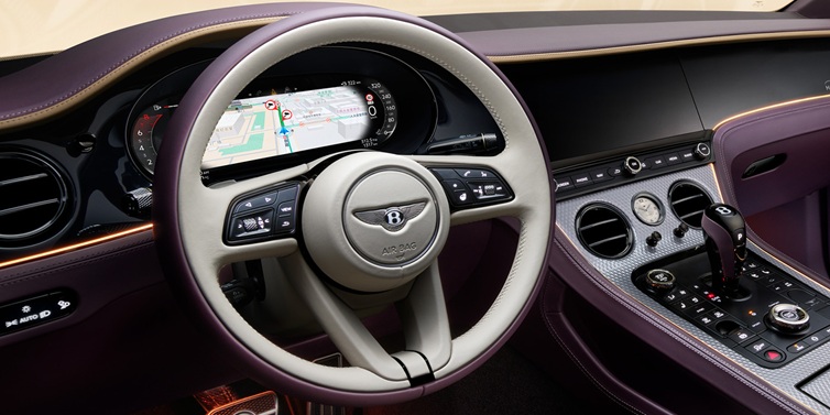 Bentley Panama Bentley Continental GT Mulliner coupe front interior showing steering wheel and drivers screens surrounded by Linen and Damson hides and Grand Black veneer